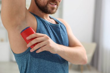 Gülümseyen adam evde deodorant sürüyor, yakın plan.