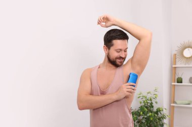 Gülümseyen adam evde katı deodorant sürüyor. Metin için boşluk
