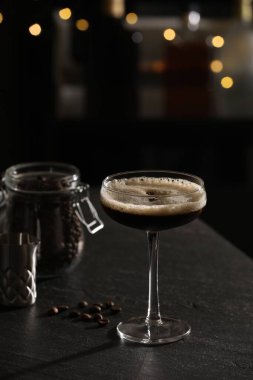 Lezzetli espresso martini ve kahve çekirdekleri ile koyu renkli masada bulanık ışıklara karşı.