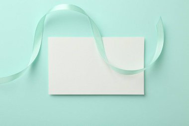 Turkuaz arka planda boş kart ve kurdele, üst görünüm