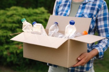 Geri dönüşüm. Elinde plastik şişelerle karton kutu tutan kadın, yakın plan.