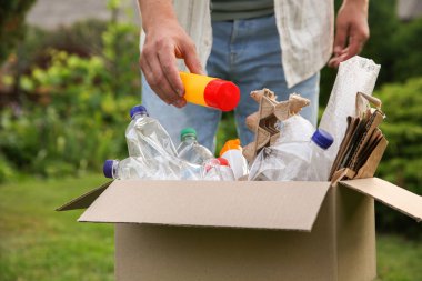 Geri dönüşüm konsepti. Dışarıdaki karton kutuya plastik şişe koyan adam.
