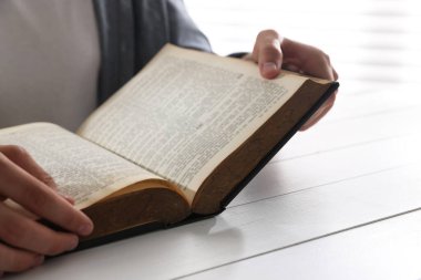 Beyaz ahşap masada İncil 'i olan adam, yakın plan.