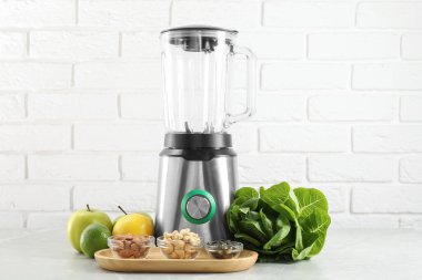 Blender ve ürünler beyaz tuğla duvara karşı ışık masasında