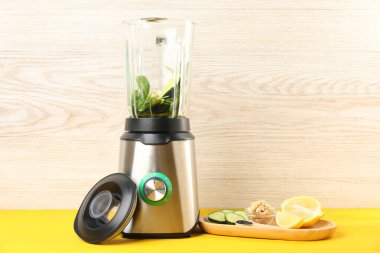 Sarı ahşap masada meyve püresi için malzemelerle modern blender. Metin için boşluk