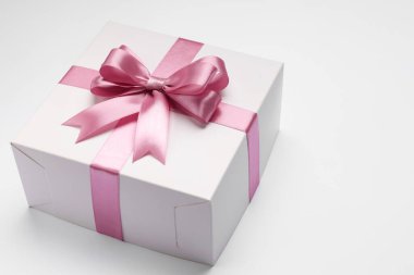 Açık gri arka planda pembe fiyonklu hediye kutusu. Metin için boşluk
