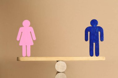 Cinsiyet eşitliği kavramı. Bej arka planda terazide erkek ve kadın figürleri