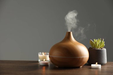 Aroma yağı yayıcı, ağaç masa üzerinde bitki ve yanan mumlar, metin için alan