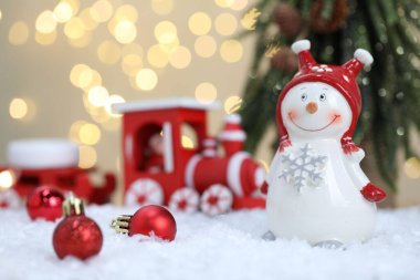 Kardan adam figürü ve bulanık ışıklara karşı yapay kar üzerindeki diğer Noel dekorları.