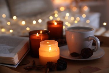 Yakıcı mumlar, ışıklar, kahve, kitap ve dekorasyon kapalı yerde, yakın plan. Sonbahar atmosferi