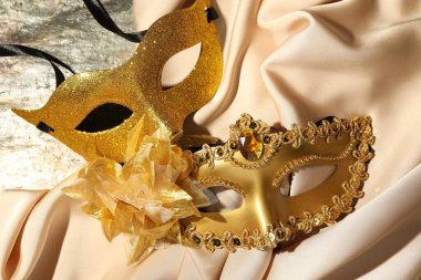 Masada güzel altın karnaval maskeleri ve bej kumaşlar var.