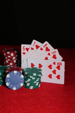 Poker fişleri ve kırmızı masada iskambil kartları