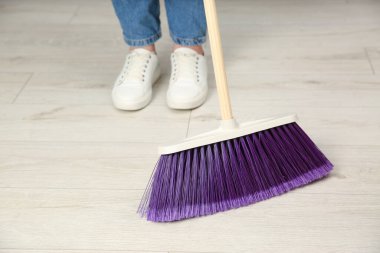 Süpürgeyle yerleri süpüren kadın, yakın plan.