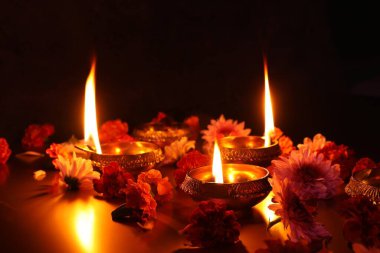 Diwali kutlaması. Diya lambaları ve koyu arkaplanda güzel çiçekler