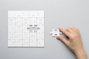 Açık gri arka planda beyaz bulmacayı çözen kadın, üst görünüm