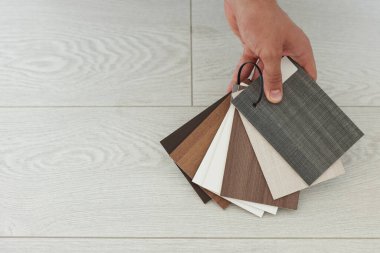 Kapalı alanda ahşap döşeme numuneleri olan bir adam, yakın plan. Metin için boşluk