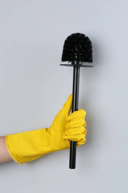 Gri arka planda siyah tuvalet fırçası tutan kadın, yakın plan. Temizlik aracı
