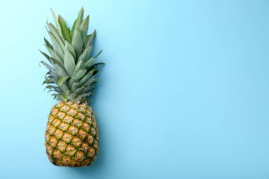 Açık mavi arka planda taze, olgun bir ananas, üst manzara. Metin için boşluk