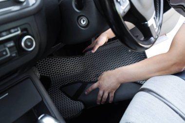 Gri lastik araba paspasını otomatikten alan adam, yakın plan.