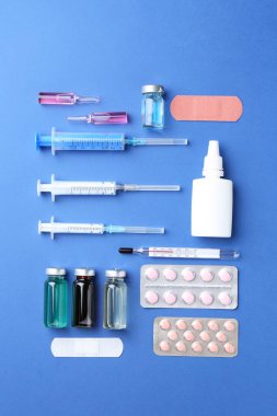 Eczacı konsepti. Mavi arka planda şişeler, şırıngalar ve haplarla düzleştirilmiş bileşim