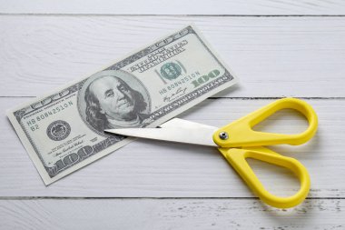 Bütçe belirleme. Beyaz ahşap masa üzerinde makasla dolar banknot, üst görünüm