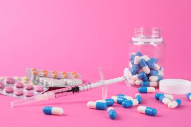 Eczacı. Pembe arka planda birçok farklı ilaç ve şırınga var.