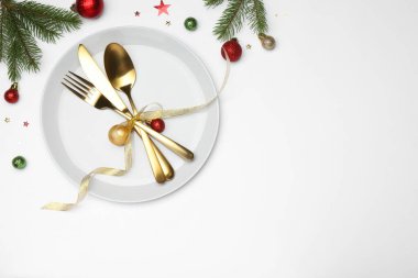 Beyaz arka planda tabak, çatal bıçak takımı ve şenlik dekoruyla Noel sofrası. Metin için boşluk
