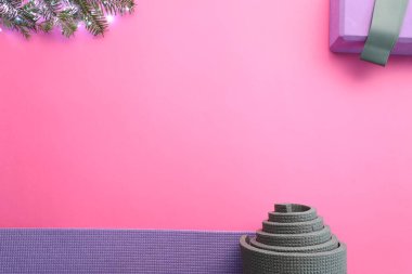 Yoga minderi, elastik bant, Noel ışıkları ve pembe arka planda köknar dalları, düz yatak. Metin için boşluk