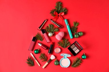 Makyaj ürünleri ve kırmızı arka planda dekor ile yapılmış Noel ağacı, düz yatıyordu