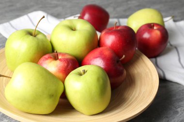 Gri masada taze kırmızı ve yeşil elmalar, yakın plan.