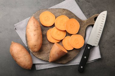 Gri masada taze çiğ patates ve bıçak.