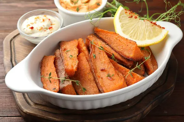 Lezzetli pişmiş patates parçaları ahşap masada servis ediliyor, yakın plan.