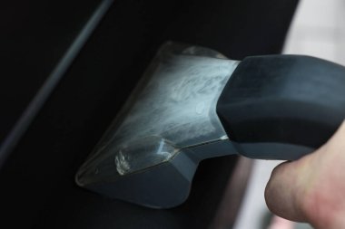 Arabanın kapısını elektrikli süpürgeyle temizleyen adam, yakın plan.