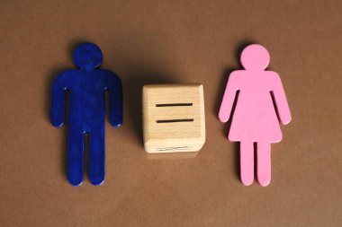 Cinsiyet eşitliği kavramı. Kahverengi arka planda erkek ve kadın figürleri var.