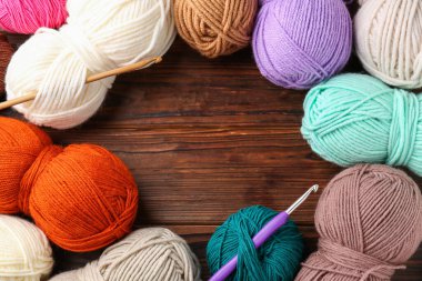 Farklı ipliklerden yapılmış çerçeve ve ahşap masa üzerine örgü kancaları, düz yatış. Metin için boşluk