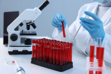 Laboratuvar testi. Doktor, kan örneği ve pipetle test tüpünü kapalı bir masada tutuyor.