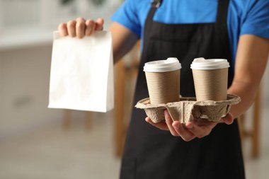 Kese kağıdı ve bardaklı fast-food işçisi, yakın plan.