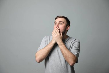 Gri arka planda korku hisseden genç adam