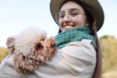 Dışarıda sevimli köpeğiyle gülümseyen kadın.