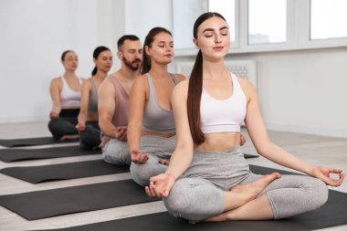 Yoga dersinde minderler üzerinde meditasyon yapan bir grup insan.