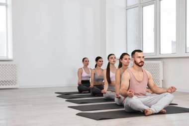 Yoga dersinde minderler üzerinde meditasyon yapan bir grup insan. Metin için boşluk