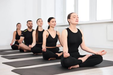 Yoga dersinde minderler üzerinde meditasyon yapan bir grup insan.