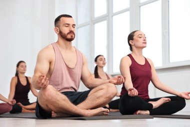 Yoga dersinde minderler üzerinde meditasyon yapan bir grup insan.