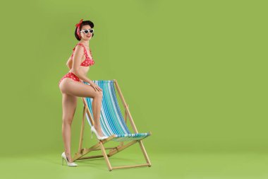 Yeşil arka planda katlanan sandalyenin yanında bikinili kadın, mesaj için yer