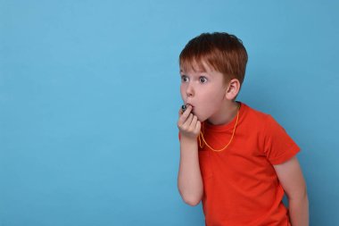 Açık mavi arka planda ıslık çalan küçük çocuk, mesaj için boşluk