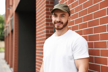 Açık hava binasının yanındaki beyzbol şapkalı gülümseyen adamın portresi. Metin için boşluk