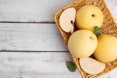 Delicious fresh apple pears in basket on white wooden table, top view. Space for text clipart