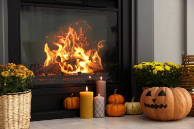 Balkabakları, yanan mumlar ve şöminenin yanındaki çiçekler. Cadılar Bayramı