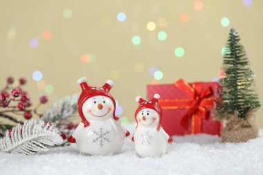 Tatlı kardan adamlar ve diğer Noel dekorları bej arka planda bulanık ışıklar, bokeh etkisi