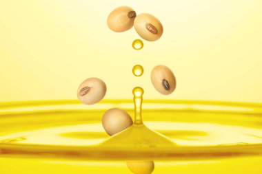 Soya fasulyesi, altın arka planda bitkisel yağın içine düşüyor.